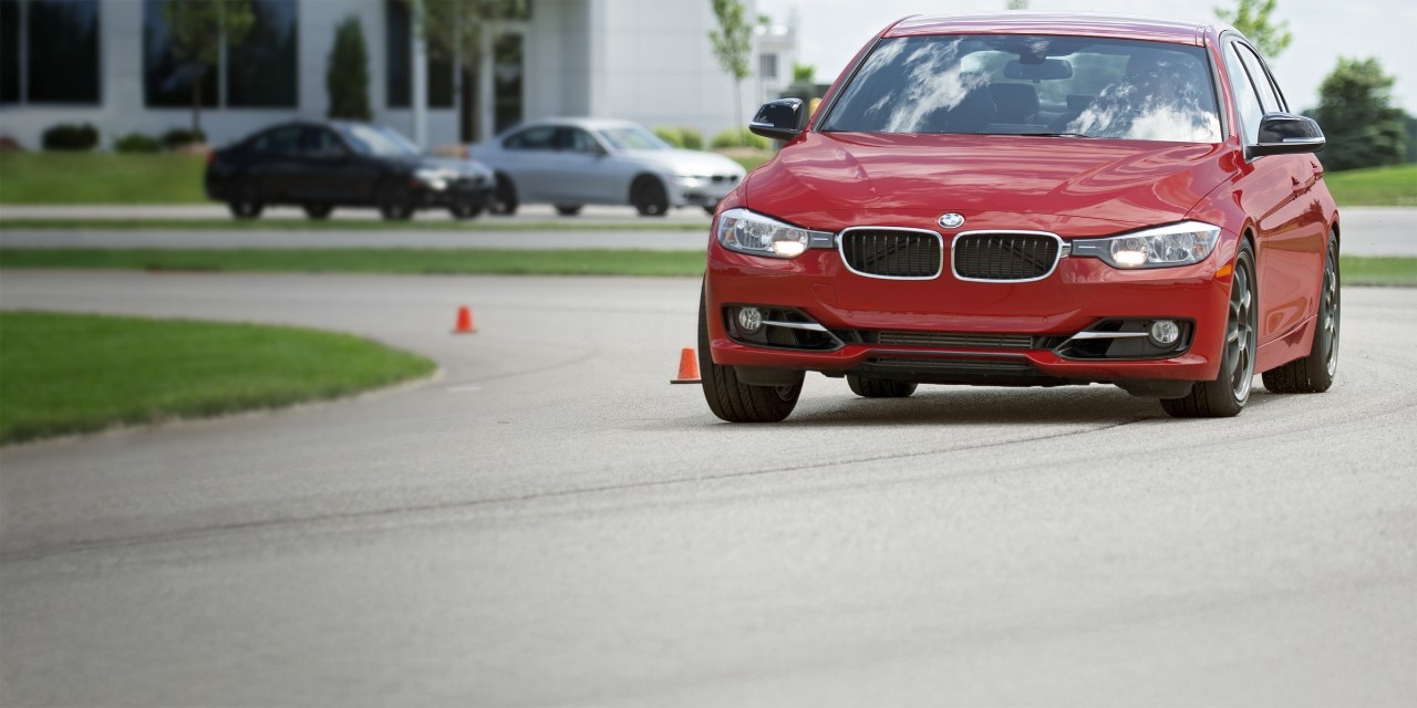 Red car driving through wet conditions on a closed course, showcasing All-Season Testing straight from the test track.