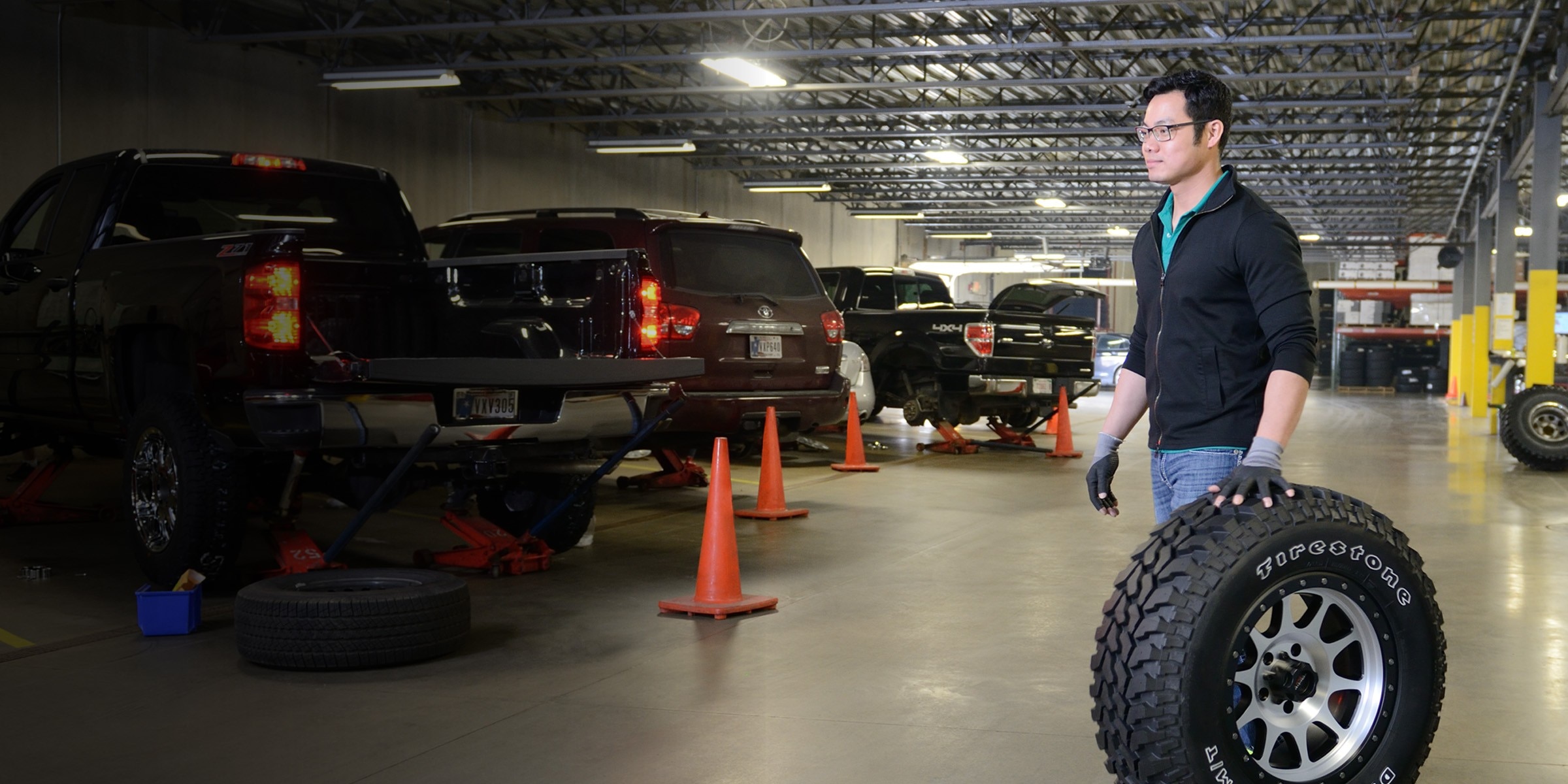 Installer rolls a tire through a service bay, ready for a scheduled installation appointment.