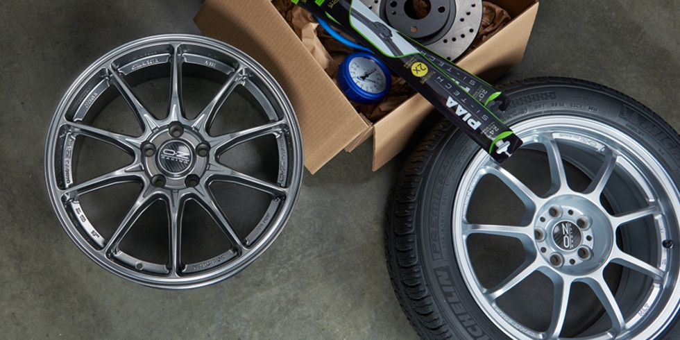 Tire Rack box with wheel, tire, and installation accessories on a garage floor for fast, free shipping.