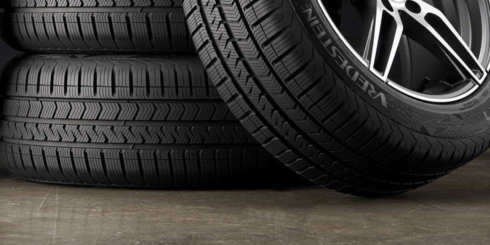 Stack of tires with a mounted tire and wheel in front, representing a tire wheel package.