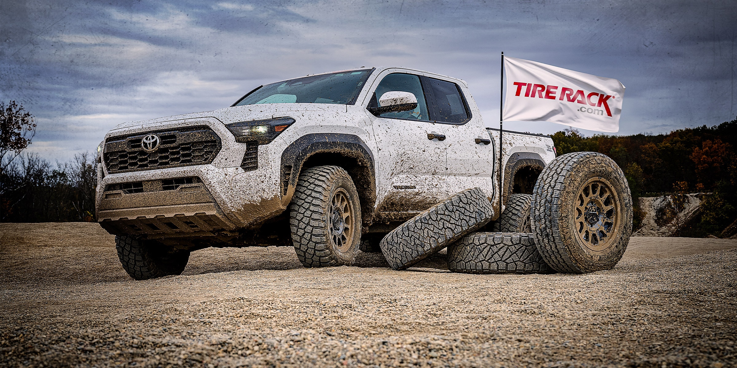 A white 2024 Toyota Tacoma TRD Off Road covered in mud after testing all-terrain & mud-terrain tires.