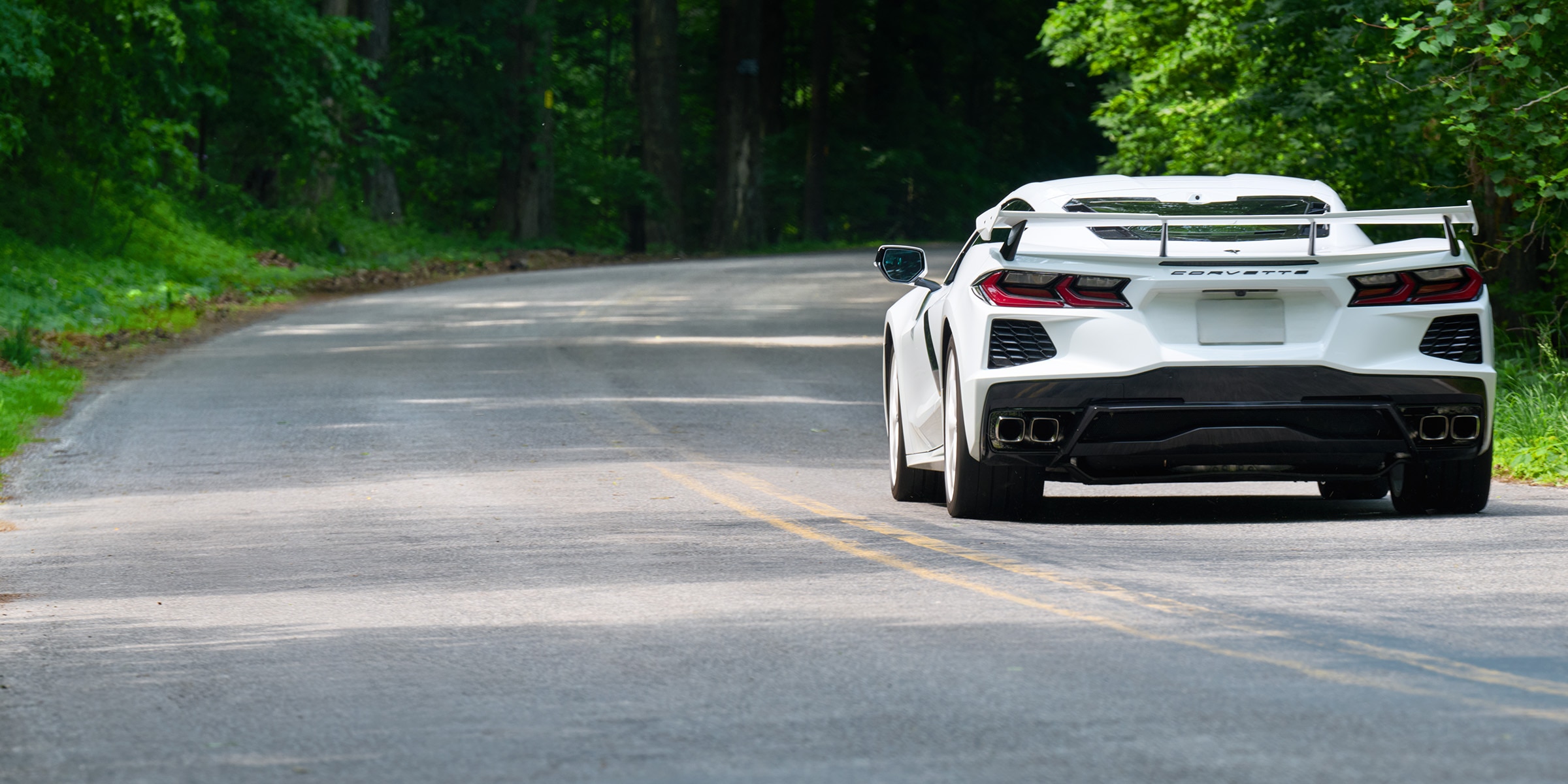 White Corvette on a winding road showcasing performance tire grip and precision handling.